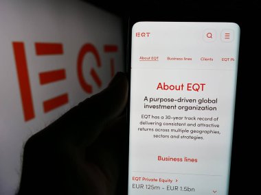 Stuttgart, Almanya - 08-13-2024: İsveçli yatırım yönetimi şirketi EQT AB 'nin web sayfası ile logo önünde cep telefonu tutan kişi. Telefon ekranının merkezine odaklan.