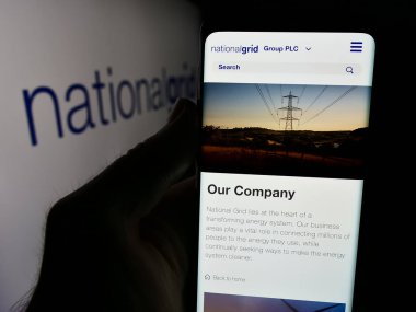Stuttgart, Almanya - 08-13-2024: İngiliz kamu hizmetleri şirketi National Grid plc 'nin web sitesi ile ticaret logosu önünde akıllı telefon tutan kişi. Telefon ekranının merkezine odaklan.