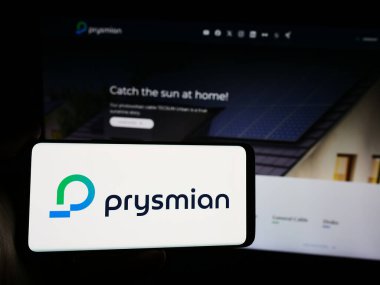 Stuttgart, Almanya - 08-13-2024: İtalyan kablo üretim şirketi Prysmian S.P.A. 'nın logosuna sahip akıllı telefon sahibi kişi web sitesinin önünde. Telefon ekranına odaklan.