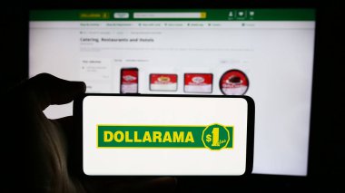 Stuttgart, Almanya - 08-15-2024: Kanada 'lı bir mağaza şirketi olan Dollarama Inc.' in logosuyla cep telefonu sahibi kişi iş sayfasının önünde. Telefon ekranına odaklan.