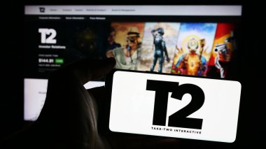 Stuttgart, Germany - 08-15-2024: Person holding smartphone with logo of US gaming company Take-Two Interactive Software Inc. in front of website. Focus on phone display. clipart