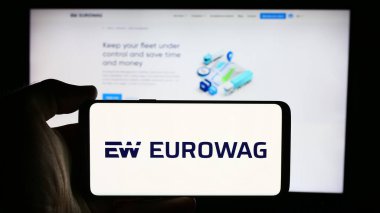 Stuttgart, Almanya - 08-15-2024: Çek W.A.G. şirketinin logosuyla cep telefonu tutan kişi Ödeme çözümleri a.s. (Eurowag) iş sayfasının önünde. Telefon ekranına odaklan.