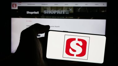 Stuttgart, Almanya - 08-15-2024: Güney Afrikalı süpermarket perakende şirketi Shoprite 'nin logosuyla cep telefonu tutan kişi iş sayfasının önünde. Telefon ekranına odaklan.