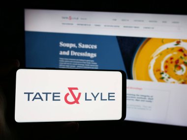 Stuttgart, Almanya - 08-16-2024: İngiliz gıda işleme şirketi Tate ve Lyle plc 'in logosuna sahip akıllı telefon sahibi kişi web sitesinin önünde. Telefon ekranına odaklan.