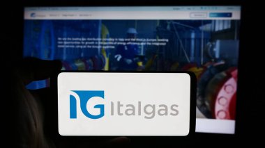 Stuttgart, Almanya - 08-16-2024: İtalyan doğalgaz dağıtım şirketi Italgas SpA 'nın logosuyla cep telefonu tutan kişi iş sayfasının önünde. Telefon ekranına odaklan.
