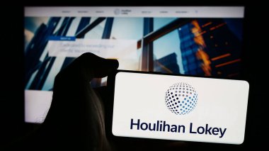 Stuttgart, Almanya - 08-16-2024: İnternet sitesi önünde ABD 'li yatırım bankacısı Houlihan Lokey Inc.' in logosuna sahip kişi. Telefon ekranına odaklan.