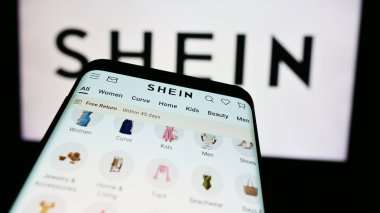 Stuttgart, Almanya - 08-16-2024: Moda e-ticaret şirketi Shein 'in web sitesi ile ticaret logosu önünde akıllı telefon. Telefon ekranının sol üst kısmına odaklan.