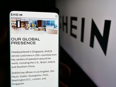 Stuttgart, Almanya - 08-16-2024: Moda e-ticaret şirketi Shein 'in web sayfası olan cep telefonunu ticari logonun önünde tutan kişi. Telefon ekranının merkezine odaklan.