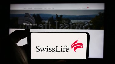 Stuttgart, Almanya - 08-16-2024: İsviçreli Hayat Tutma AG sigorta şirketinin logosuyla cep telefonu tutan kişi iş sayfasının önünde. Telefon ekranına odaklan.