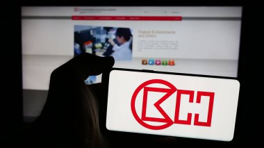 Stuttgart, Almanya - 08-16-2024: Hong Kong şirketi CK Hutchison Holding Limited 'in logosuna sahip cep telefonu sahibi kişi iş sayfasının önünde. Telefon ekranına odaklan.