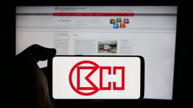 Stuttgart, Almanya - 08-16-2024: Hong Kong şirketi CK Hutchison Holding Limited 'in logosuna sahip cep telefonu sahibi kişi iş sayfası önünde. Telefon ekranına odaklan.