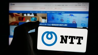 Stuttgart, Germany - 08-18-2024: Person holding smartphone with logo of company Nippon Telegraph and Telephone Corporation (NTT) in front of website. Focus on phone display. clipart