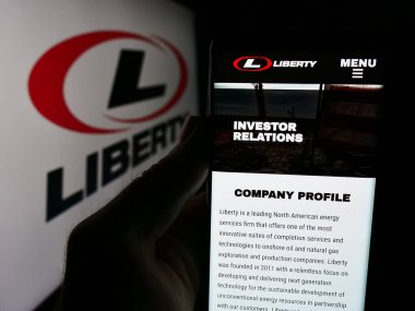 Stuttgart, Almanya - 08-18-2024: ABD 'li petrol hizmetleri şirketi Liberty Energy Inc.' in internet sayfası ile logo önünde cep telefonu tutan kişi. Telefon ekranının merkezine odaklan.