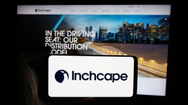 Stuttgart, Almanya - 08-18-2024: İngiliz otomotiv dağıtım şirketi Inchcape plc 'in logosuna sahip cep telefonu sahibi kişi iş sayfasının önünde. Telefon ekranına odaklan.