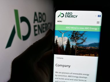 Stuttgart, Almanya - 08-18-2024: Alman yenilenebilir enerji şirketi ABO Energy GmbH Co. KGaA 'nın web sitesi ile logo önünde akıllı telefon bulunduran kişi. Telefon ekranının merkezine odaklan.
