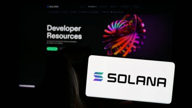 Stuttgart, Almanya - 08-18-2024: Ticari web sayfası önünde blockchain şirketi Solana 'nın logosuna sahip cep telefonu sahibi kişi. Telefon ekranına odaklan.