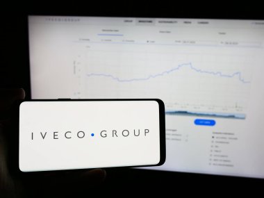 Stuttgart, Almanya - 08-18-2024: İtalyan ticari araç şirketi Iveco Group NV 'nin logosuyla cep telefonu sahibi kişi iş sayfasının önünde. Telefon ekranına odaklan.