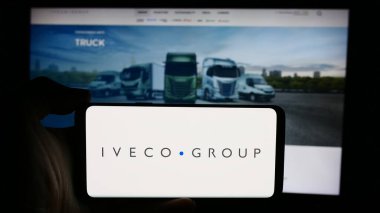 Stuttgart, Almanya - 08-18-2024: İtalyan ticari araç şirketi Iveco Group N.V. 'nin logosuyla cep telefonu sahibi kişi iş sayfasının önünde. Telefon ekranına odaklan.