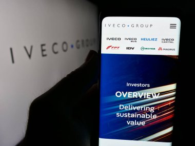 Stuttgart, Almanya - 08-18-2024: İtalyan ticari araç şirketi Iveco Group N.V. 'nin web sayfası ile logo önünde akıllı telefon tutan kişi. Telefon ekranının merkezine odaklan.