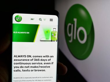 Stuttgart, Almanya - 08-19-2024: Nijeryalı telekomünikasyon şirketi Globacom Limited 'in (Glo) internet sayfası ile akıllı telefon tutan kişi. Telefon ekranının merkezine odaklan.
