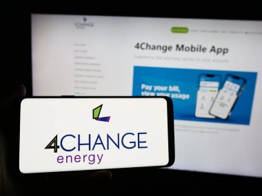 Stuttgart, Germany - 08-19-2024: Person holding smartphone with logo of US retail electricity company 4Change Energy in front of website. Focus on phone display. clipart