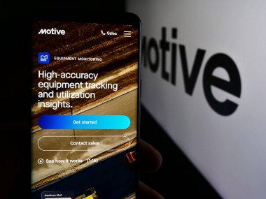 Stuttgart, Almanya - 08-19-2024: ABD 'li kamyonculuk yazılım şirketi Motive Technologies Inc.' nin logolu web sayfası ile cep telefonu tutan kişi. Telefon ekranının merkezine odaklan.