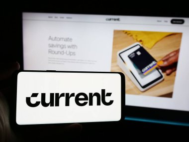 Stuttgart, Almanya - 08-19-2024: İnternet sayfası önünde Amerikan fintech şirketi Current 'in (Finco Services Inc.) logosuna sahip cep telefonu sahibi kişi. Telefon ekranına odaklan.