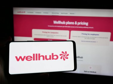 Stuttgart, Almanya - 08-19-2024: Web sitesi önünde kurumsal sağlık şirketi Wellhub 'un (Gympass US LLC) logosuna sahip akıllı telefon sahibi kişi. Telefon ekranına odaklan.