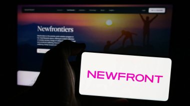 Stuttgart, Almanya - 08-19-2024: Amerikan finans şirketi Newfront Sigorta Hizmetleri 'nin logosunun bulunduğu cep telefonu sahibi kişi web sayfasının önünde. Telefon ekranına odaklan.