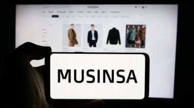 Stuttgart, Almanya - 08-19-2024: Güney Koreli moda şirketi MUSINSA Co. Ltd. nin logosuyla cep telefonu tutan kişi iş sayfasının önünde. Telefon ekranına odaklan.