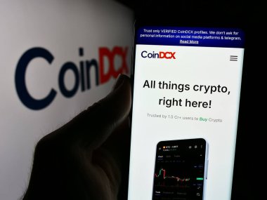Stuttgart, Almanya - 08-19-2024: Hintli Kripto Yatırım Uygulama Şirketi CoinDCX 'in logo önündeki web sayfası ile cep telefonu tutan kişi. Telefon ekranının merkezine odaklan.
