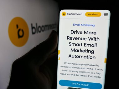 Stuttgart, Almanya - 08-19-2024: ABD e-ticaret platformu şirketi Bloomreach Inc. 'in web sayfası ile logo önünde cep telefonu tutan kişi. Telefon ekranının merkezine odaklan.