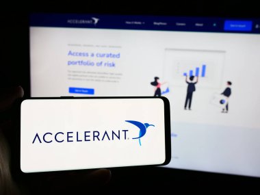 Stuttgart, Germany - 08-19-2024: Person holding mobile phone with logo of American risk exchange company Accelerant in front of business web page. Focus on phone display. clipart