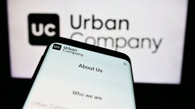 Stuttgart, Almanya - 08-20-2024: Hintli ev hizmetleri pazar yeri şirketi Urban Company 'nin web sitesi ile birlikte iş logosu önünde cep telefonu. Telefon ekranının sol üst kısmına odaklan.