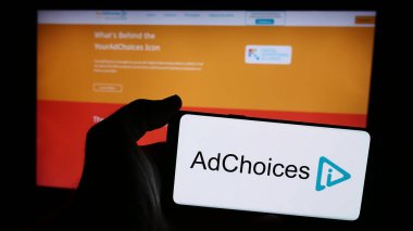 Stuttgart, Almanya - 08-20-2024: İnternet sitesi önünde reklam şeffaflığı çözümü (AdChoices) logosuna sahip akıllı telefon sahibi kişi. Telefon ekranına odaklan.