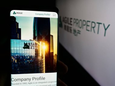 Stuttgart, Almanya - 08-20-2024: Çin şirketi Agile Property Holding Limited 'in internet sayfası ile cep telefonu tutan kişi logonun önünde. Telefon ekranının merkezine odaklan.