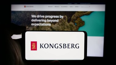 Stuttgart, Almanya - 08-20-2024: Norveçli firma Kongsberg Gruppen ASA 'nın logosuyla cep telefonu tutan kişi iş sayfasının önünde. Telefon ekranına odaklan.