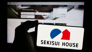 Stuttgart, Almanya - 08-20-2024: Japon ev yapımı şirketi Sekisui House Ltd. 'nin logosuna sahip akıllı telefon sahibi kişi web sitesinin önünde. Telefon ekranına odaklan.