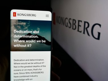 Stuttgart, Almanya - 08-20-2024: Norveçli firma Kongsberg Gruppen ASA 'nın internet sayfası ile akıllı telefon sahibi kişi iş logosu önünde. Telefon ekranının merkezine odaklan.