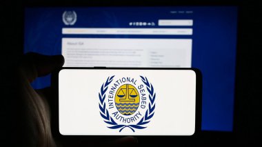 Stuttgart, Almanya - 08-21-2024: Uluslararası Deniz Yatağı Otoritesi (ISA) örgütünün logosuna sahip cep telefonu sahibi kişi iş sayfası önünde. Telefon ekranına odaklan.