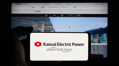 Stuttgart, Almanya - 08-21-2024: İnternet sayfası önünde Japon şirketi Kansai Electric Power Co. Inc. (KEPCO) 'nun logosuyla cep telefonu bulunduran kişi. Telefon ekranına odaklan.