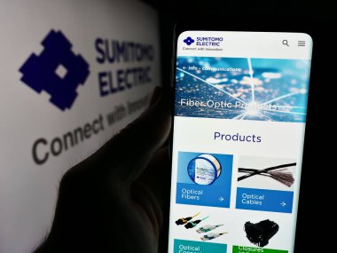 Stuttgart, Almanya - 08-21-2024: Japon şirketi Sumitomo Electric Industries Ltd. 'nin internet sayfası ile logo önünde cep telefonu tutan kişi. Telefon ekranının merkezine odaklan.