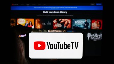 Stuttgart, Almanya - 08-21-2024: İş sayfası önünde ABD 'li IPTV hizmet YouTube TV logosu taşıyan cep telefonu sahibi kişi. Telefon ekranına odaklan.