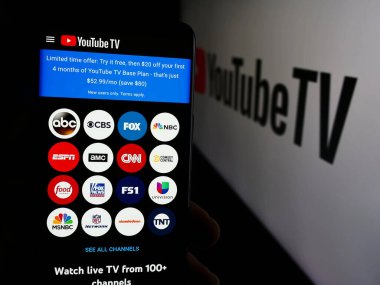 Stuttgart, Almanya - 08-21-2024: İş logosu önünde ABD IPTV hizmet YouTube TV web sayfası ile cep telefonu tutan kişi. Telefon ekranının merkezine odaklan.