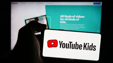 Stuttgart, Almanya - 08-21-2024: Amerikan video paylaşım platformu şirketi Youtube Kids 'in logosunun bulunduğu cep telefonu sahibi kişi web sayfası önünde. Telefon ekranına odaklan.