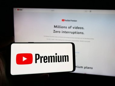 Stuttgart, Almanya - 08-21-2024: İnternet sitesi önünde video akışı abonelik hizmeti YouTube Premium logosuna sahip akıllı telefon sahibi kişi. Telefon ekranına odaklan.