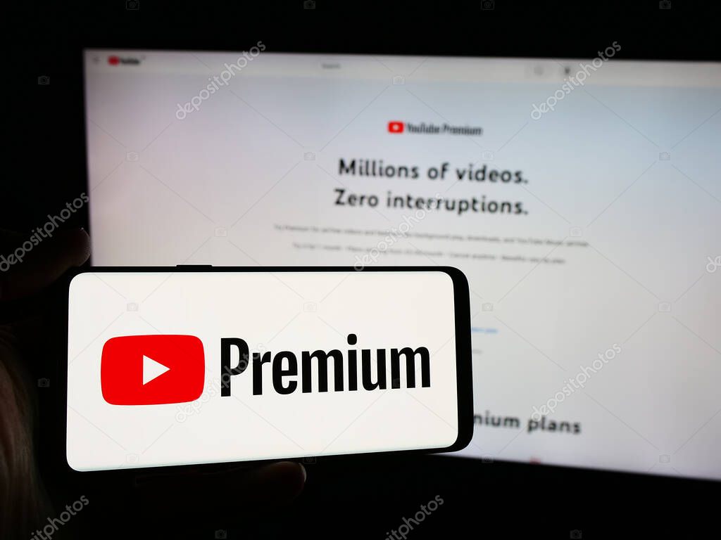 Stuttgart, Germany - 08-21-2024: Person holding smartphone with logo of video streaming subscription service YouTube Premium in front of website. Focus on phone display.