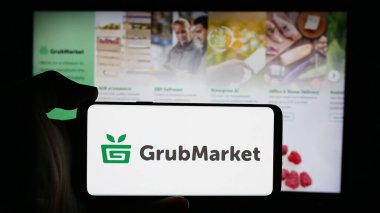 Stuttgart, Almanya - 08-22-2024: Amerikan Gıda Teknolojisi Şirketi GrubMarket Inc. 'in logosuyla cep telefonu tutan kişi iş sayfasının önünde. Telefon ekranına odaklan.
