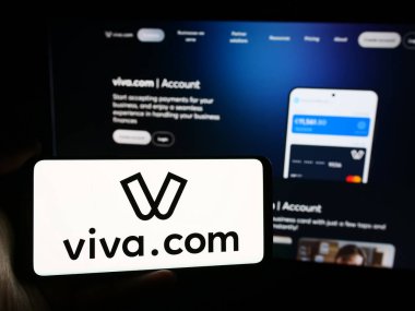 Stuttgart, Almanya - 08-22-2024: Yunan ödeme şirketi Viva Payments 'ın (Viva.com) logosuyla cep telefonu sahibi kişi iş sayfasının önünde. Telefon ekranına odaklan.