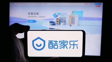 Stuttgart, Almanya - 08-24-2024: Çinli çevrimiçi bilgi şirketi Kujiale 'in logosuyla cep telefonu tutan kişi iş sayfasının önünde. Telefon ekranına odaklan.